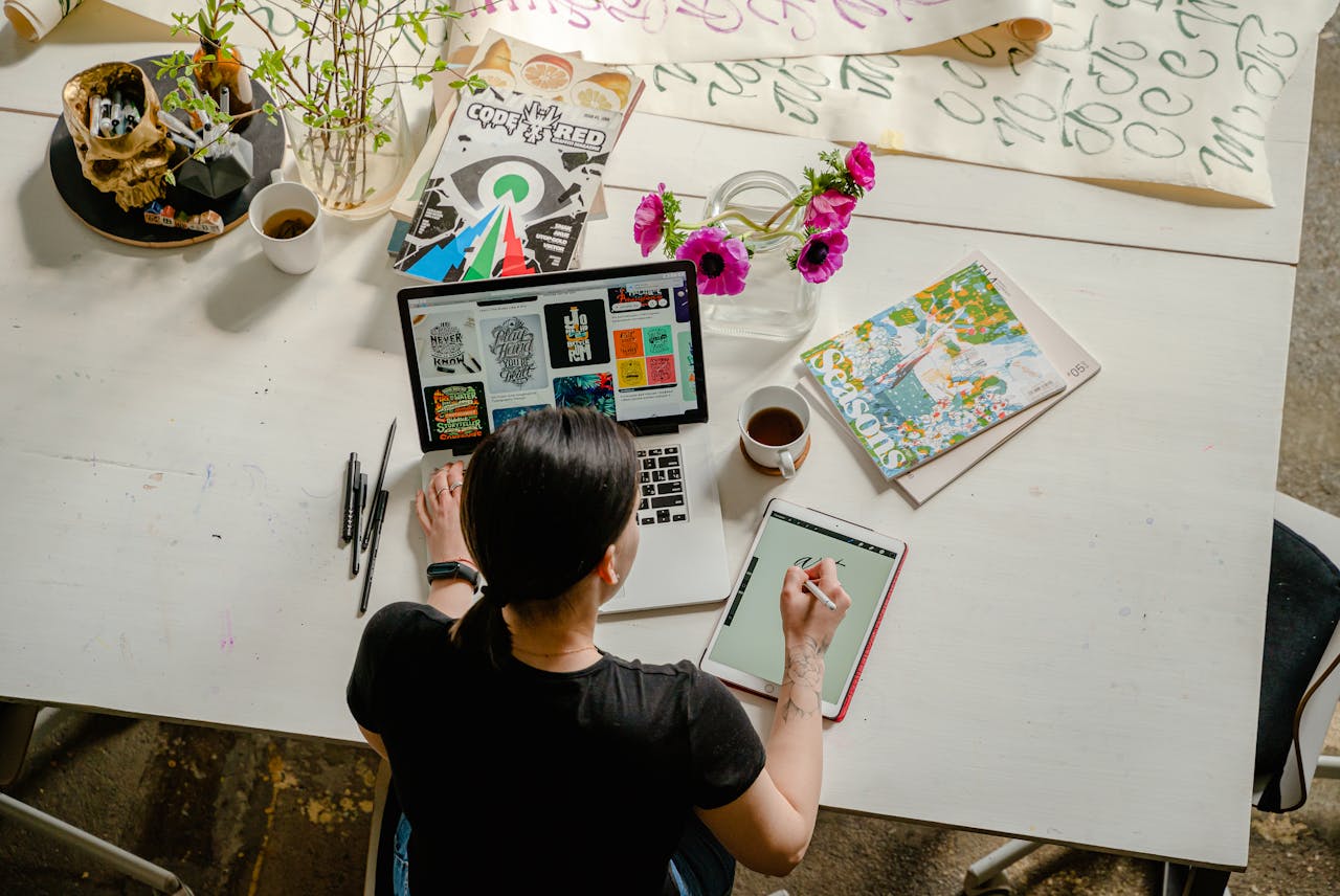 about-us Artistic workspace featuring calligraphy and digital design on a tablet and laptop.