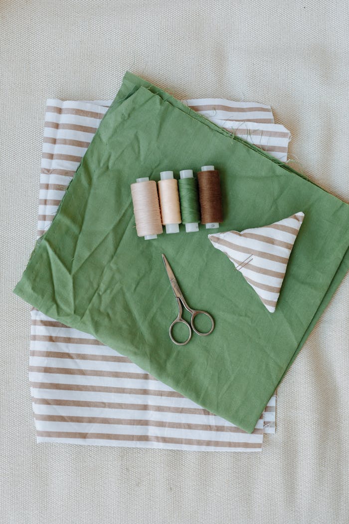 services-01 A flat lay of sewing tools and striped fabric with scissors and threads.