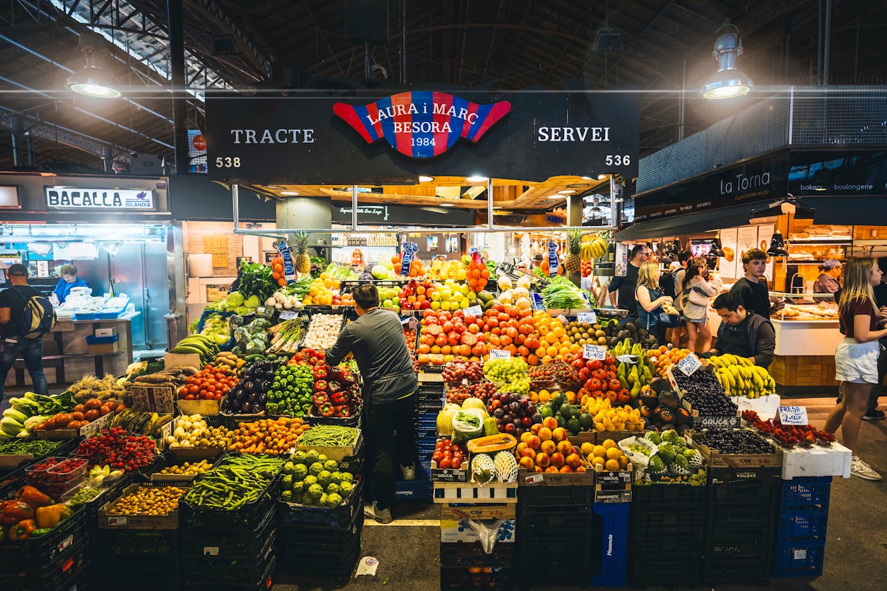 Colorful market stall displaying fresh fruits and vegetables in Barcelona's bustling market.