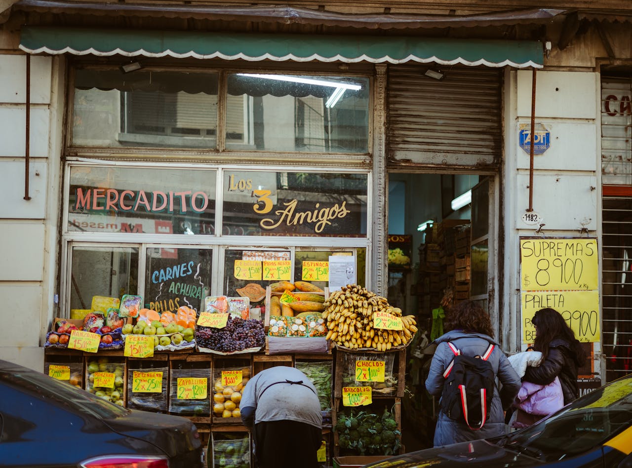 About Street view of a local market 'Los Tres Amigos' in Buenos Aires with people shopping for fresh produce.