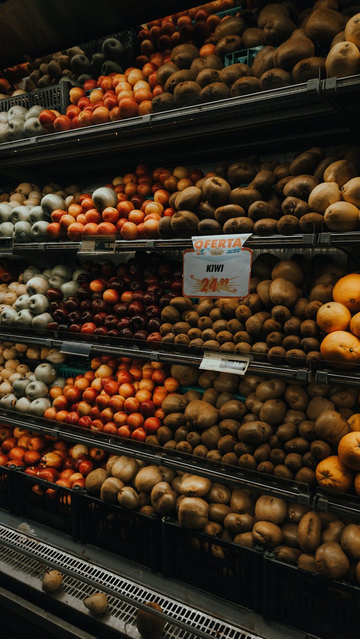 Colorful assortment of fruits and vegetables in a market setting with a price tag highlighting a kiwi offer.